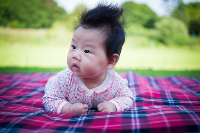 Baby lying on a red blanket outdoors, symbolising new beginnings and balance in Feng Shui baby naming and BaZi analysis.
