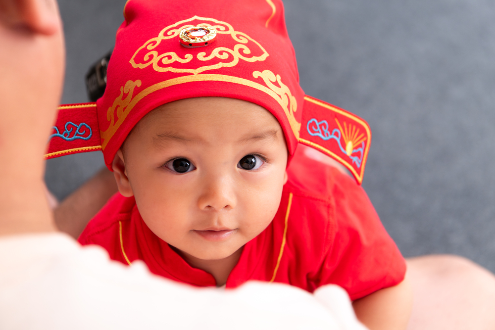 Portrait of child in Chinese New Year celebration clothes Baby dressed in a traditional red outfit symbolising good fortune and balance, representing how a Feng Shui master for baby name uses BaZi analysis and the five elements to align a child’s destiny and energy.