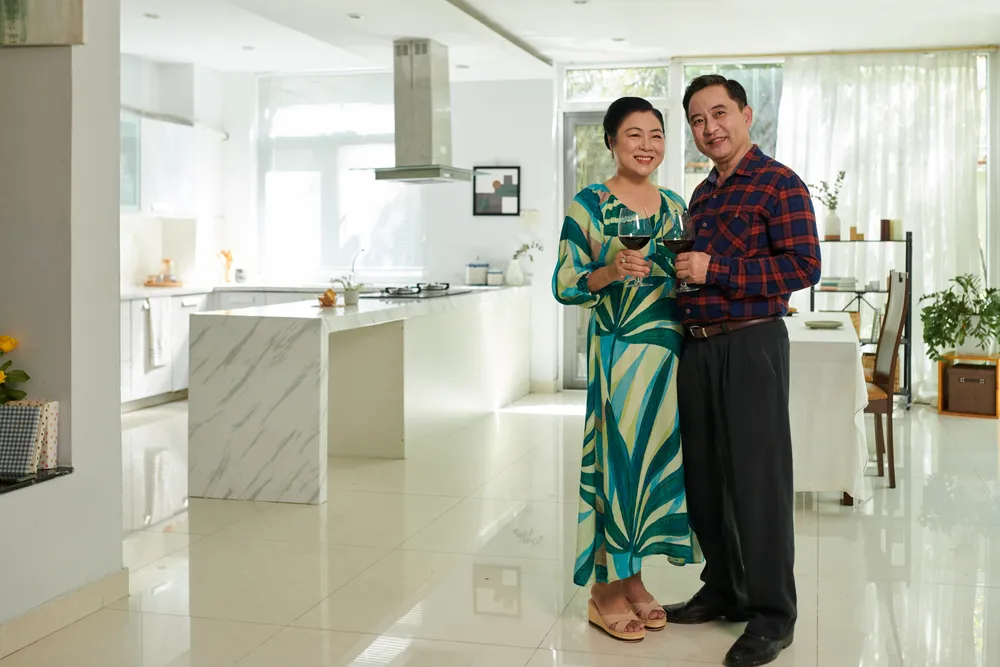 property-timing-bazi-analysis-singapore Happy middle-aged couple standing in their modern Singapore home, celebrating successful property investment guided by BaZi analysis.