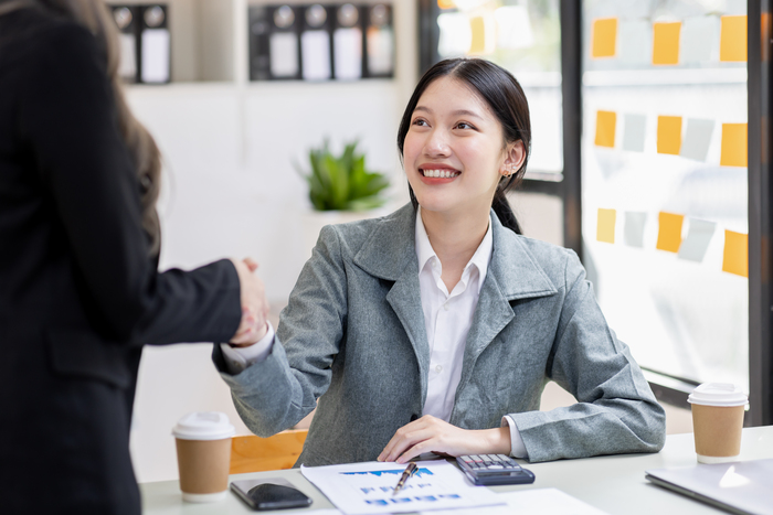 Smiling woman shaking hands after a meeting, reflecting success and BaZi analysis in Singapore.