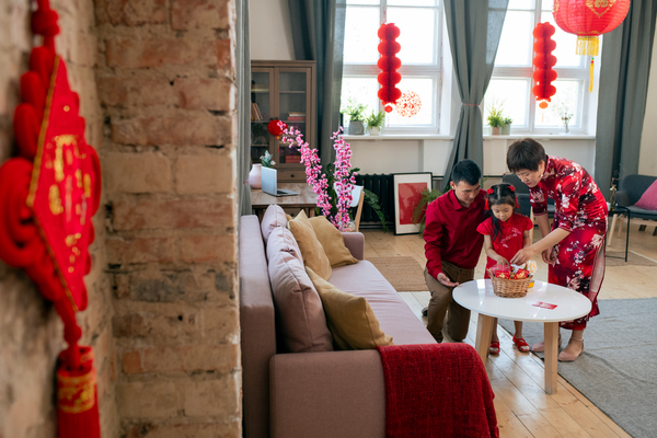 family in a Feng Shui-inspired living room arranging Lunar New Year decorations, showcasing how residential Feng Shui services help create a harmonious and prosperous home environment.